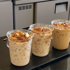 three desserts in plastic cups sitting on a table next to each other with ice cream and granola