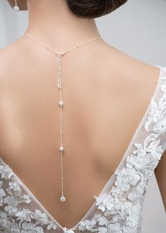 the back of a woman's wedding dress with a long necklace on her neck