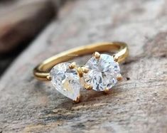 two heart shaped diamond engagement rings sitting on top of a rock