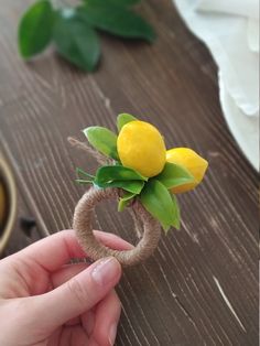 a person is holding a ring with lemons on it and some leaves in the background