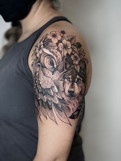 a woman's arm with a wolf and flowers tattoo on her left shoulder, next to a black mask