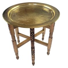 an antique brass tray with wooden legs and designs on the top, sitting on a white background