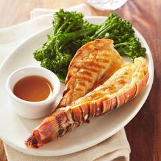 lobster, broccoli and dipping sauce on a white plate with a wooden table