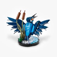 a blue lego bird with two bottles in it's beaks sitting on top of a plant