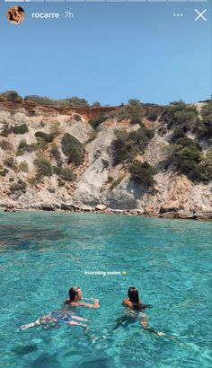 two people are swimming in the clear blue water