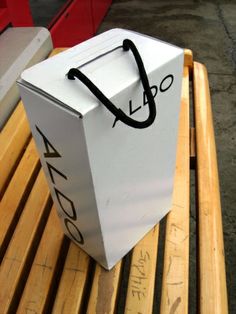 a white bag sitting on top of a wooden bench next to a red box with the word lago written on it