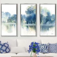 three paintings are hanging on the wall above a white couch with blue and white pillows