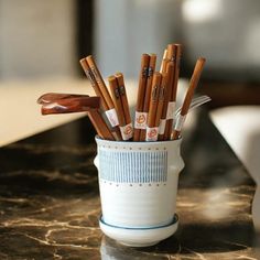 a cup filled with wooden utensils on top of a table