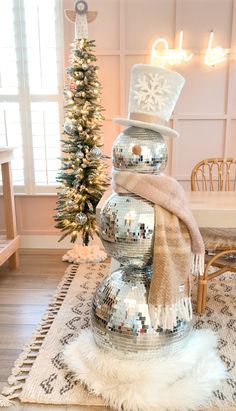 a snowman made out of disco balls on top of a rug next to a christmas tree