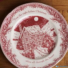 a red and white plate with an image of a house in the woods on it