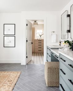 a bathroom with white walls and gray flooring next to a large mirror on the wall