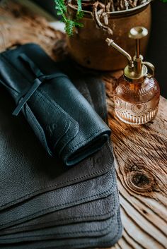 a black leather wallet sitting on top of a wooden table next to a vase with flowers