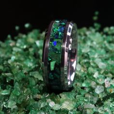 "This is the Emerald Forest Ring, primarily made with Emerald and two different green opals on a black and green background and glows green. Emerald is the birthstone of May, making it my birthstone! Green is one of my favorite colors as well so this ring is automatically one of my favorites! The primarily pictured band is made of Tungsten-Carbide, which is very durable, scratch-resistant, and has a nice heft to it. This ring is perfect for all occasions and can even make the perfect wedding ban Green Opal Wedding Jewelry, Green Opal Promise Ring, Green Opal Ring For Anniversary, Green Opal Ring Gift, Green Opal Ring As A Gift, Anniversary Green Opal Ring, Green Luminous Round Jewelry, Glow In The Dark Wedding, Black And Green Background