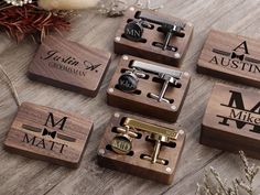 four wooden cufflinks with personalized names on them and some flowers in the background