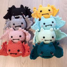 four crocheted stuffed animals sitting next to each other on a wooden floor in different colors