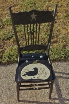 a black chair with a bird painted on it's back and stars in the seat