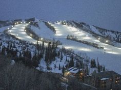 a ski slope covered in lots of snow and lit up by street lights at night