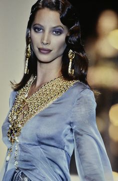 a woman in a blue dress and gold jewelry