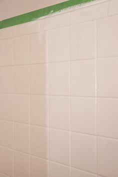 a white tiled wall with green tape on it