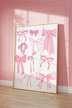 a pink and white framed artwork with bows on it in front of a pink wall