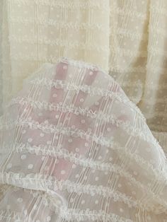 an umbrella with white lace on it sitting in front of curtained window sill