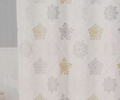 a white shower curtain with gold and silver snowflakes on it in a bathroom