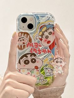 a woman holding up her phone case with stickers on it's sides and an image of cartoon characters on the back