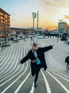 a woman is running in the middle of an empty parking lot with people walking around