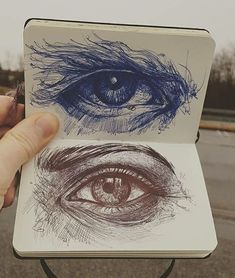 a hand holding up a notebook with an eye drawn on the front and back cover