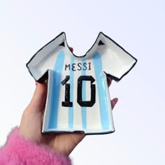 a hand holding a ceramic soccer jersey ornament with the number 10 on it