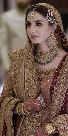 a woman wearing a gold and red bridal outfit