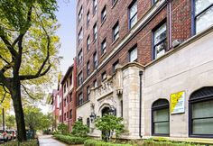 an apartment building in the city with trees and bushes on both sides of the street