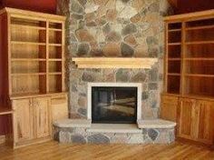 an empty living room with stone fireplace and built - in bookcases