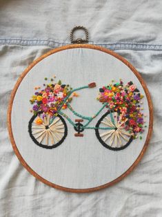 a close up of a embroidery on a piece of cloth with a bike and flowers