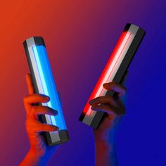 two hands holding electronic devices with colored lights on them in the same hand, one is red and blue