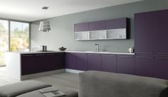 a modern kitchen with purple cabinets and white counter tops, along with a gray couch