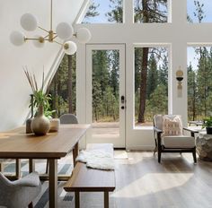 a living room filled with furniture and lots of windows next to a wooden dining table