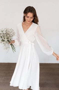 a woman wearing a white dress and holding a bouquet of flowers in her right hand