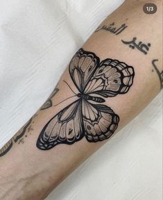 a black and white butterfly tattoo on the arm