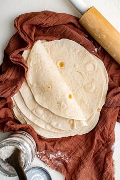 floured tortillas on a red cloth with rolling pin