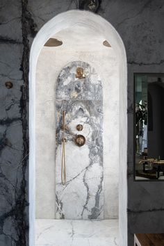 a bathroom with marble and gold fixtures on the wall, along with an arched doorway