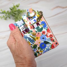 a woman's hand holding a colorful floral purse