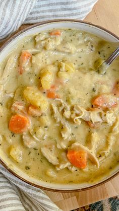 a bowl of chicken and dumpling soup with a spoon in it on a table