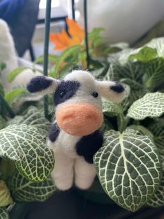 a small stuffed cow sitting on top of a plant