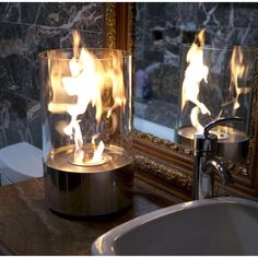 a bathroom sink sitting under a mirror next to a fire lamp on top of a counter