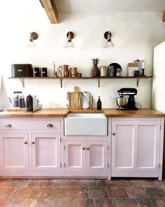 a kitchen with pink cabinets and shelves filled with pots, pans and other items