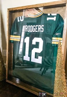 a green and gold football jersey in a wooden frame with glitters on the floor