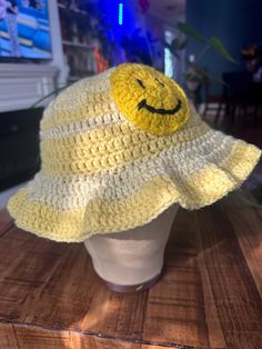 a crocheted hat with a smiley face on the front sits on a table