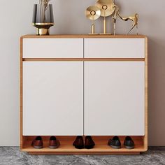 a white cabinet with two doors and three pairs of shoes sitting on top of it