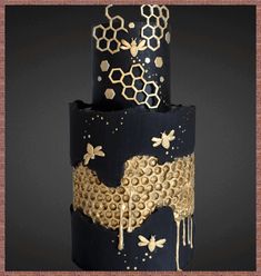 a three tiered cake with honeycombs and bees on the side, decorated in gold foil